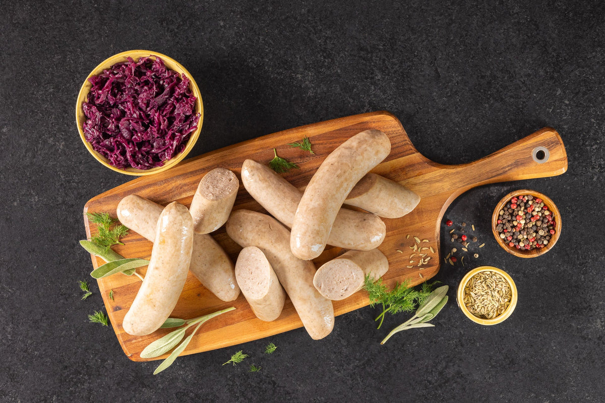 Opa's Bratwurst links on a wooden board with red cabbage, mustard and peppercorns