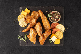 Opa's Peppered Cured Smoked Turkey Breast, sliced, on a slate board with cheese and crackers