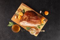 Opa's honey glazed half ham, spiral sliced, on a cutting board with oranges