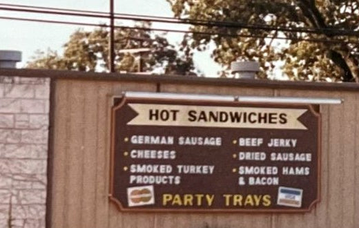 Vintage Opa's sign listing hot sandwiches, German sausage, cheeses, smoked turkey, jerky, hams and bacon, and party trays